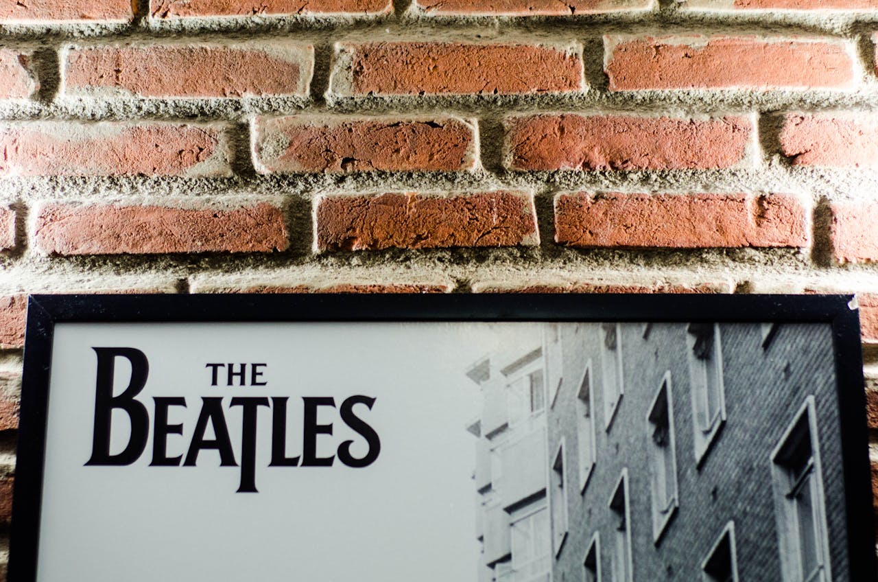A vintage Beatles poster against a classic brick wall background, emphasizing retro style.